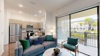 Located in Oviedo, FL, this thoughtfully designed one-bedroom, one-bathroom residence offers a modern open-concept layout that maximizes its efficient footprint. The combined living and kitchen area serves as the heart of the home, featuring recessed lighting, wood-look flooring, and a large sliding glass door that floods the space with natural light and opens to a private balcony overlooking the surrounding community. The contemporary kitchen is outfitted with light wood cabinetry, a marble-style tile backsplash, stainless steel appliances including a range, microwave, and dishwasher, and a deep sink beneath a window. A welcoming hallway connects the main living area to the private quarters, lined with white panel doors and accented by wood-look flooring throughout. The bedroom is a comfortable retreat with ample space for a full furniture arrangement, a ceiling fan, and direct access to a dedicated closet. The bathroom features a tub-shower combination with elegant marble-style tile surround, wood-tone vanity cabinetry, and hardwood-style flooring. Clean white walls and recessed lighting throughout the residence create a bright, cohesive ambiance ideal for modern living.