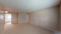 This single-floor residence offers a practical and comfortable layout designed for everyday living. The spacious living area is finished with soft wall-to-wall carpeting and neutral beige walls, creating a warm and inviting atmosphere. Large windows with blinds allow natural light to fill the room, enhancing its open feel. A secondary living or dining area provides additional flexible space, also carpeted and bathed in natural light.

The galley-style kitchen is efficiently designed with warm hardwood flooring, white cabinetry, and speckled countertops. It is equipped with a double-basin sink, a coil-burner electric range, a dishwasher, and a full-size refrigerator. A rear door in the kitchen leads directly outside, adding convenience and bringing in additional natural light.

The bedroom is generously sized, featuring plush carpeting, a ceiling fan with light fixture, a large window overlooking the outdoors, and two closets — including a walk-in — providing ample storage. The full bathroom includes warm hardwood flooring, a single-sink vanity with storage cabinetry, and a tub/shower combination with tile surround. Throughout the unit, the clean, neutral palette and functional design provide a comfortable and move-in-ready living environment.
