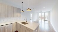 Located in Chicago's dynamic Uptown neighborhood, this two-bedroom, two-bathroom residence offers a thoughtfully designed open-concept layout that seamlessly connects the kitchen, dining, and living areas. The kitchen is a standout feature, appointed with light wood cabinetry, striking marble-look quartz countertops, a subway tile backsplash, and a full suite of stainless steel appliances including a gas range, built-in microwave, and dishwasher. A central island with pendant lighting adds both function and style. The living area is bathed in natural light from floor-to-ceiling sliding glass doors that open to a private patio, offering open city views. Warm hardwood flooring flows throughout the main living spaces and both bedrooms, complementing the clean, neutral palette. The bedrooms are generously proportioned, with the primary suite offering ample closet space. The hallway provides additional dedicated closet and laundry areas for added convenience. Both bathrooms are finished with white subway tile and clean modern fixtures, including a full soaking tub. A ceiling fan in the living area and recessed lighting throughout complete this well-appointed urban residence.