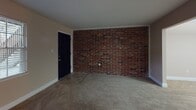 Located at 6100 Waters Ave in Savannah, Georgia, this single-floor unit offers a straightforward and functional layout across several well-defined living spaces. The living area greets residents with warm neutral-toned walls, wall-to-wall carpeting, and a front entry door that opens to a striking exposed brick accent wall, lending the space a distinctive, character-rich aesthetic. Natural light filters in through a window fitted with blinds, brightening the open feel of the room.

The bedrooms continue the neutral color palette with plush carpeting underfoot and ceiling fans with integrated lighting for year-round comfort. One bedroom features a bold terracotta accent wall paired with a pendant light fixture, adding a touch of visual interest. HVAC vents are present throughout for climate control.

The kitchen is equipped with white cabinetry, a double-basin stainless steel sink, laminate countertops, and a white electric range with overhead ventilation — providing all the essentials for everyday cooking. Vinyl flooring completes the practical design of this space.

The bathroom includes a full tub and shower combination surrounded by white square tile, complemented by a grab bar for added safety and convenience. Throughout the unit, clean lines, consistent finishes, and functional details make this a practical and comfortable living space in Savannah's 31406 area.