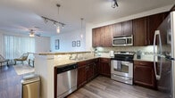 This thoughtfully designed single-floor residence offers 1 bedroom and 2 bathrooms within a comfortable and functional layout. The open-concept kitchen and living area serves as the heart of the home, featuring rich dark-stained cabinetry, granite countertops, a subway tile backsplash, and a full suite of stainless steel appliances including a dishwasher, range, microwave, and refrigerator. A peninsula with seating provides a casual dining option and enhances the kitchen's connection to the living space. Warm wood-look flooring flows throughout the main areas, adding cohesion and character. The living room is bright and inviting, highlighted by a ceiling fan, large sliding glass doors with vertical blinds, and ample space for relaxed living. The bedroom offers plush carpeting, a window with natural light, and access to a generously sized walk-in closet outfitted with multiple shelving tiers and hanging rods. The primary bathroom features a dual-sink vanity with dark wood cabinetry, a soaking tub with shower, and wood-look tile flooring. A hallway connects the rooms efficiently. Throughout the residence, clean white walls, modern fixtures, and consistent finishes create a polished, move-in-ready environment.