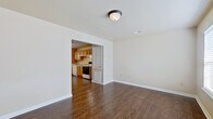 This two-floor home offers a practical and well-organized layout with consistent finishes throughout. The main level welcomes you through a front entry door flanked by sidelight windows, opening into a bright living area with dark hardwood-style flooring and neutral walls that create a clean, versatile backdrop. The living space connects directly to a galley-style kitchen, which features warm honey-toned wood cabinetry lining both walls, light countertops, white appliances including a range, dishwasher, and refrigerator, and a pendant light fixture above a window that brings in natural light. A washer and dryer are conveniently accommodated within the kitchen area. A half bath on the main level includes a wood-vanity with an integrated sink and hardwood-style flooring. The upper level hosts multiple bedrooms finished with soft carpeting and panel-style doors, providing comfortable and quiet spaces. A full bathroom on the upper level features a tub-shower combination, toilet, and a wood-vanity, finished with warm hardwood-style flooring. Throughout the home, six-panel doors, clean white trim, and neutral wall tones create a cohesive and understated aesthetic.