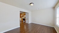 This two-floor home offers a practical and well-organized layout with consistent finishes throughout. The main level welcomes you through a front entry door flanked by sidelight windows, opening into a bright living area with dark hardwood-style flooring and neutral walls that create a clean, versatile backdrop. The living space connects directly to a galley-style kitchen, which features warm honey-toned wood cabinetry lining both walls, light countertops, white appliances including a range, dishwasher, and refrigerator, and a pendant light fixture above a window that brings in natural light. A washer and dryer are conveniently accommodated within the kitchen area. A half bath on the main level includes a wood-vanity with an integrated sink and hardwood-style flooring. The upper level hosts multiple bedrooms finished with soft carpeting and panel-style doors, providing comfortable and quiet spaces. A full bathroom on the upper level features a tub-shower combination, toilet, and a wood-vanity, finished with warm hardwood-style flooring. Throughout the home, six-panel doors, clean white trim, and neutral wall tones create a cohesive and understated aesthetic.
