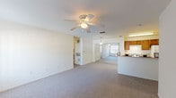 This single-floor residence offers a well-organized layout that balances open communal areas with private living spaces. The living room serves as the central gathering area, featuring soft carpet flooring, a ceiling fan with integrated lighting, and a large window dressed with vertical blinds that allows natural light to fill the room. A tiled entryway provides a clean transition from the front door into the main living space. The living area flows openly toward a dining area, which is illuminated by a pendant light fixture.

The galley-style kitchen is efficiently designed with warm wood cabinetry, light countertops, a double stainless steel sink, and white appliances including a gas range, refrigerator, and dishwasher. A tile floor adds durability to this functional cooking space.

The bedrooms are carpeted and bright, each featuring ceiling fans, windows with vertical blinds for natural light and privacy, and bifold closet doors offering generous storage. The rooms maintain a clean, neutral aesthetic throughout.

The bathrooms are practical and well-appointed. One features a wood vanity with a light countertop and a tub/shower combination, while the other offers a tiled tub/shower surround. Together, the spaces present a comfortable and move-in-ready residence with a consistent, understated design throughout.