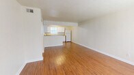Located at 820 Arkansas St in Tallahassee, Florida, this two-bedroom, one-bathroom home offers a practical and comfortable single-floor layout. The living room serves as the heart of the home, featuring warm wood-look flooring that extends throughout the main areas, neutral walls, and a large window that invites natural light and outdoor views. The space flows seamlessly into the kitchen, which is equipped with white cabinetry, light countertops, a double sink, an electric range, and a refrigerator — all arranged in a functional U-shaped layout with a pass-through counter connecting to the living area. Both bedrooms are carpeted for comfort and feature ceiling fans with integrated lighting, windows with blinds, and closets with classic six-panel doors. The primary bedroom offers a generous footprint with ample wall space. The shared bathroom includes a tiled shower-tub combo, a wood-toned vanity with a light stone countertop, and wood-look flooring, maintaining a cohesive aesthetic throughout. A hallway connects the bedrooms and bathroom, providing a well-organized flow. The overall ambiance is clean, bright, and move-in ready, with a consistent neutral palette throughout.