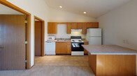 Located at 2415 W Bradley Ave in Champaign, Illinois, this single-floor unit offers a practical and comfortable layout designed for everyday living. The open-concept living and kitchen area is a standout feature, with soaring vaulted ceilings and a ceiling fan that enhance the sense of spaciousness. Natural light streams in through a large window, brightening the carpeted living space. A built-in counter or breakfast bar provides a natural transition into the kitchen, which is equipped with warm oak cabinetry, recessed lighting, tile flooring, and a full suite of white appliances including a refrigerator, electric range, dishwasher, and microwave. The kitchen also benefits from vaulted ceiling lines, adding to its airy feel. The bedrooms are carpeted and well-proportioned, each featuring closet space with shelving for ample storage. One bedroom includes a ceiling-mounted light fixture and a window with outdoor views. The full bathroom is clean and functional, featuring a tiled floor, a tub-shower combination, and a vanity. Throughout the unit, warm wood-toned trim and doors provide consistent, cohesive detailing. The overall ambiance is bright, neutral, and move-in ready.