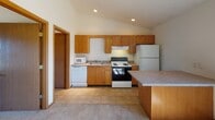 Located at 2415 W Bradley Ave in Champaign, Illinois, this single-floor unit offers a practical and comfortable layout designed for everyday living. The open-concept living and kitchen area is a standout feature, with soaring vaulted ceilings and a ceiling fan that enhance the sense of spaciousness. Natural light streams in through a large window, brightening the carpeted living space. A built-in counter or breakfast bar provides a natural transition into the kitchen, which is equipped with warm oak cabinetry, recessed lighting, tile flooring, and a full suite of white appliances including a refrigerator, electric range, dishwasher, and microwave. The kitchen also benefits from vaulted ceiling lines, adding to its airy feel. The bedrooms are carpeted and well-proportioned, each featuring closet space with shelving for ample storage. One bedroom includes a ceiling-mounted light fixture and a window with outdoor views. The full bathroom is clean and functional, featuring a tiled floor, a tub-shower combination, and a vanity. Throughout the unit, warm wood-toned trim and doors provide consistent, cohesive detailing. The overall ambiance is bright, neutral, and move-in ready.
