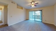 This single-floor residence is thoughtfully laid out to maximize functionality across its key living areas. The main living space is bright and open, featuring plush blue-toned carpet, a textured ceiling, and a ceiling fan with integrated lighting. A full-width sliding glass door fitted with vertical blinds opens directly onto a private balcony, allowing generous natural light to fill the room. A tiled entryway at the front door provides a practical transition point into the carpeted living area.

The galley-style kitchen is efficiently designed with warm wood cabinetry lining both sides, light-toned countertops, tile flooring, and white appliances including a range, microwave, refrigerator, and dishwasher. A utility closet is accessible directly from the kitchen.

The two bedrooms are each finished with neutral carpet and ceiling fans, and both feature windows with blinds that bring in outdoor views and natural light. One bedroom includes a walk-in closet with shelving, while the other offers a standard closet. The bathroom is finished with tile flooring, a single-sink vanity with wood cabinetry, a wall mirror, and a towel bar, maintaining a clean and functional aesthetic consistent with the rest of the space.