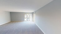 Located at 1141 Lighthouse Ave in the charming coastal city of Pacific Grove, California, this single-floor unit offers a well-organized layout with modern finishes throughout. The living area is generously sized, featuring soft wall-to-wall carpeting and large sliding glass doors that flood the space with natural light while providing direct access to a private balcony overlooking treetop and neighborhood views. The open-concept kitchen is a functional highlight, equipped with rich dark espresso cabinetry, light quartz countertops, stainless steel appliances including a range, microwave, dishwasher, and refrigerator, plus a peninsula that adds both prep space and a natural division from the living area. Light wood-look flooring runs through the kitchen, complementing the contemporary design. The bedroom is a comfortable, carpeted retreat with its own sliding door balcony access and ample closet space. Two bathrooms serve the unit — one featuring a tub-shower combo with white tile surround, a quartz vanity, and wood-look flooring, and a second equally clean and functional bathroom. Soft gray walls and crisp white trim are consistent throughout, lending the space a clean, neutral palette well-suited to a variety of interior styles.
