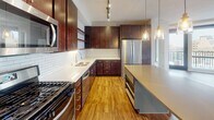 This single-floor unit at 801–809 CR-152 E in Minneapolis showcases a contemporary urban design with a thoughtful layout and high-quality finishes throughout. The open-concept kitchen and living area serves as the heart of the space, featuring warm hardwood flooring that extends seamlessly through the main areas. The kitchen is well-equipped with rich, dark-stained cabinetry offering generous storage, stainless steel appliances including a gas range and refrigerator, a white quartz countertop, and a subway tile backsplash. A central island with a neutral countertop provides additional prep space and casual seating. Track and pendant lighting illuminate the kitchen effectively.

The living area is bright and open, benefiting from floor-to-ceiling windows that frame views of the surrounding Minneapolis cityscape and invite substantial natural light. Exposed concrete columns add an industrial character that complements the modern aesthetic. The bedroom continues the urban loft feel with large windows, carpeted flooring, a ceiling fan, and exposed concrete accents.

Two bathrooms offer clean, modern finishes, including large-format tile flooring and white subway tile surrounds. One bathroom features a soaking tub and shower combination, while the second includes a glass-enclosed walk-in shower, a dark wood vanity, and ample counter space. The overall ambiance is contemporary and polished.