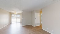 This single-floor residence offers a practical and well-organized layout highlighted by a consistent neutral color palette and light wood-style flooring throughout the main living areas. The spacious living room receives natural light through a large sliding glass door fitted with vertical blinds, which also provides access to an outdoor patio area. A ceiling fan adds functional comfort to the space, which features a textured ceiling finish found throughout the unit.

The kitchen is efficiently designed with white cabinetry, granite-style countertops, and a full suite of white appliances including a gas range, dishwasher, refrigerator, and range hood. A window above the sink allows additional natural light into the cooking area.

Two bedrooms are carpeted for comfort, each featuring vertical blind-covered windows and closets with built-in shelving. The unit includes two full bathrooms, each outfitted with a tub-shower combination, a granite-style vanity countertop, white cabinetry, and light wood-style flooring. One bathroom includes a lighted mirror and wall-mounted shelving. Overall, the space maintains a clean, functional, and move-in-ready character.