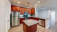 Located in Lawrenceville, GA, this well-appointed single-story home offers three bedrooms, three bathrooms, and a thoughtfully designed layout. The living room is a standout space, featuring a tray ceiling with crown molding, a classic white-mantled fireplace, and glass doors that invite natural light and outdoor views. Rich wood-look flooring flows throughout the main living areas, complemented by a neutral, light gray color palette.

The kitchen is a functional centerpiece, showcasing warm cherry wood cabinetry, granite countertops, a center island, a teal subway tile backsplash, and a full suite of stainless steel appliances. Crown molding and recessed lighting add a polished finish, with an arched passageway connecting the kitchen to the entrance foyer.

The bedrooms are carpeted for comfort, each equipped with a ceiling fan and ample natural light from large windows with views of surrounding greenery. The generously sized primary bedroom includes a walk-in closet with wire shelving. The bathrooms are finished with wood-look vinyl flooring, white cabinetry, granite counters, and tile-surround bathtubs. A dedicated laundry room with built-in shelving and washer hookups completes this practical and comfortable home.