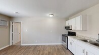 Located at 171 Wallace Blvd in Clarksville, Tennessee, this one-bedroom, one-bathroom unit offers a practical and well-appointed single-floor layout. The open kitchen and living area features durable wood-style flooring throughout, neutral gray walls, and a bright, clean aesthetic. The kitchen is equipped with stainless steel appliances — including a gas range, over-the-range microwave, and refrigerator — paired with white shaker-style cabinetry and granite-look countertops with an undermount sink, providing both functionality and a modern touch. The living area flows naturally from the kitchen, offering a versatile open space with ample room to furnish comfortably. The bedroom is carpeted for warmth and comfort, featuring a ceiling fan with light fixture, a window with blinds that invites natural light, and access to a dedicated closet. The full bathroom includes a white vanity with cabinet storage, a framed mirror, and a shower-tub combo. Neutral tones are carried throughout the unit, creating a cohesive and move-in-ready atmosphere. A utility closet with an electrical panel rounds out the layout. This unit is well-suited for individuals or couples seeking a compact, efficiently designed home in Clarksville.