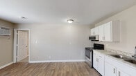 Located at 171 Wallace Blvd in Clarksville, Tennessee, this one-bedroom, one-bathroom unit offers a practical and well-appointed single-floor layout. The open kitchen and living area features durable wood-style flooring throughout, neutral gray walls, and a bright, clean aesthetic. The kitchen is equipped with stainless steel appliances — including a gas range, over-the-range microwave, and refrigerator — paired with white shaker-style cabinetry and granite-look countertops with an undermount sink, providing both functionality and a modern touch. The living area flows naturally from the kitchen, offering a versatile open space with ample room to furnish comfortably. The bedroom is carpeted for warmth and comfort, featuring a ceiling fan with light fixture, a window with blinds that invites natural light, and access to a dedicated closet. The full bathroom includes a white vanity with cabinet storage, a framed mirror, and a shower-tub combo. Neutral tones are carried throughout the unit, creating a cohesive and move-in-ready atmosphere. A utility closet with an electrical panel rounds out the layout. This unit is well-suited for individuals or couples seeking a compact, efficiently designed home in Clarksville.