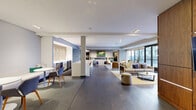 Located at 240 Chicago Ave in Minneapolis, MN, this expansive amenity floor offers a thoughtfully designed collection of spaces for recreation, fitness, and socializing. The open-plan lounge area serves as the centerpiece, featuring wide-plank hardwood flooring, recessed lighting, and floor-to-ceiling windows that flood the space with natural light and provide views of the outdoor terrace. Comfortable seating arrangements, including plush sofas, accent chairs, and bar-height tables, create distinct zones for relaxing or gathering. A built-in linear fireplace and a striking wood-paneled media wall with mounted displays add warmth and visual interest throughout. The game room is equipped with a billiard table, a built-in wet bar with modern cabinetry, and cozy banquette seating — ideal for entertaining. The fitness center is a standout amenity, outfitted with cardio machines including treadmills and ellipticals, power racks, free weights, cable systems, and stability equipment, all set beneath linear LED lighting. A vibrant gradient accent wall energizes the space, while large windows bring in natural light. The hallway connects each area seamlessly, contributing to the floor's cohesive, contemporary aesthetic throughout.