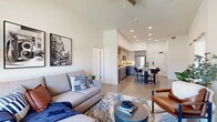 Located in the heart of downtown Sacramento at 251 6th St, this thoughtfully designed 2-bedroom, 2-bathroom residence offers a modern open-concept layout across a single floor. The living room impresses with soaring ceilings, a ceiling fan, and a striking slatted wood accent wall framing the TV, complemented by large windows that invite natural light and city views. Polished concrete floors flow seamlessly into the kitchen, which is outfitted with sleek grey cabinetry, white subway tile backsplash, quartz countertops, stainless steel appliances, and a versatile island with bar seating — ideal for dining and entertaining. The second bedroom doubles effectively as a flexible space with an accent slatted wall and large windows overlooking the Sacramento skyline. The spacious primary bedroom features plush carpeting and direct access to a well-appointed en-suite bathroom complete with a soaking tub, extended vanity with quartz countertops, and a barn door leading into a generous walk-in closet. A second full bathroom, in-unit laundry, and ample closet storage round out the functional offerings of this contemporary urban residence.