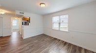 This single-floor residence offers a thoughtfully organized layout with distinct living zones connected by wood-look hardwood flooring throughout the main areas. The entry foyer welcomes visitors with a charming arched transom window above the front door, with crown molding and chair rail detailing lending architectural character to the hallway and adjoining dining area.

The galley-style kitchen is efficiently designed with warm wood cabinetry, granite-look countertops, and stainless steel appliances including a gas range, over-the-range microwave, and refrigerator. A window at the end of the kitchen brings in natural light, and a stacked washer and dryer unit is conveniently integrated into the space. A pass-through opening connects the kitchen to the dining area, enhancing the sense of openness.

The dining area features hardwood-look flooring, a window overlooking the outdoors, and a flush ceiling light fixture. Adjacent living spaces provide comfortable flow throughout the home.

The bedroom is generously sized with plush carpeting, a ceiling fan, a bright window with outdoor views, and a sliding-door closet offering ample storage. The full bathroom is finished with neutral subway tile surrounding the tub-shower combination, wood-look flooring, and a window for natural ventilation.