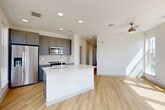 Located at 1450 Morrison Road in Denver, CO, this contemporary residence offers three bedrooms and three bathrooms across a single, thoughtfully designed floor. The open-concept living, dining, and kitchen area serves as the heart of the home, bathed in natural light streaming through expansive windows that frame impressive views of the Denver skyline and surrounding landscape. Light wood-tone flooring flows throughout the main living spaces, complementing the clean, modern aesthetic.

The kitchen is a standout feature, equipped with sleek gray shaker cabinetry, a white quartz island with an integrated sink, subway tile backsplash, and a full suite of stainless steel appliances. A ceiling fan anchors the adjacent living area, which opens to an outdoor space through a glass door.

The bedrooms are carpeted for comfort, each filled with natural light and offering closet storage. The primary bedroom includes an en-suite bathroom, while all three bathrooms are finished with gray vanity cabinets, light wood-tone flooring, and tub-shower combinations featuring marble-style tile surrounds.

A dedicated laundry area, utility room, and a bright hallway with recessed lighting complete this well-appointed residence, delivering a polished, move-in-ready living experience in the heart of Denver.