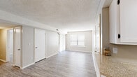 Located at 8605 Newton Ave in Kansas City, MO, this single-floor residence offers a clean, neutral aesthetic throughout its well-organized layout. The open living area is finished with light gray wood-style flooring that extends across the main living spaces, complemented by textured ceilings and warm beige walls that create a bright, cohesive atmosphere. Large windows fitted with white blinds allow natural light to filter in generously, enhancing the sense of openness. A front entry door with paneled detailing leads directly into the spacious living area, which connects smoothly to the rest of the home.

The galley-style kitchen is well-appointed with white cabinetry, light stone-finish countertops, a stainless steel refrigerator, an electric range, a dishwasher, and a double sink positioned beneath a window. The layout maximizes storage and functionality along both sides of the corridor.

The bedrooms feature plush carpeting, individual windows for natural light, and ceiling fans for added comfort. The bathroom area includes a wide vanity with white cabinetry, a large mirror with overhead lighting, and generous counter space, with a separate water closet visible beyond. The space maintains a consistent, understated design throughout.