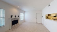 Located at 9201 Riverside Pkwy in Tulsa, Oklahoma, this single-floor residence offers a well-designed layout with a comfortable, functional flow throughout. The bright and open living area serves as the heart of the home, featuring plush carpeting, recessed lighting, and a classic tile-surround fireplace that adds warmth and character. Natural light filters in through multiple windows, and a glass-panel door opens directly to a private balcony, extending the living space outdoors. The tiled entryway provides a clean transition into the carpeted main area. The kitchen is efficiently arranged in a U-shaped configuration, showcasing white cabinetry, white countertops, hardwood flooring, and stainless steel appliances including a range, over-the-range microwave, and dishwasher — offering ample storage and counter space for everyday cooking. The bedroom is generously sized, carpeted, and equipped with a ceiling fan and light fixture, with multiple windows inviting natural light and views of surrounding greenery. The bathroom features a white vanity with a large mirror, a tub-shower combination, and tile flooring, completing the space with a clean, practical finish throughout.
