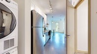 Located at 657 22nd Avenue Northeast in Minneapolis's vibrant Northeast neighborhood, this efficiently designed single-floor unit makes smart use of its compact footprint. Polished concrete floors flow throughout the open layout, lending an industrial-modern aesthetic that ties the space together cohesively.

The kitchen is a standout feature, outfitted with stainless steel appliances including a refrigerator, electric range, dishwasher, and built-in microwave. White upper cabinetry contrasts stylishly with grey lower cabinets, while a stainless steel wall-mounted range hood and open shelving add a contemporary touch. A peninsula with a white quartz countertop provides additional prep space and casual seating. Track lighting and a pendant globe light illuminate the area effectively.

The living area benefits from natural light provided by a window facing the exterior, complemented by a ceiling fan and pendant lighting that enhance the airy atmosphere of the space.

The full bathroom is clean and bright, featuring a white vanity with a quartz countertop, a tub/shower combo, and brushed nickel fixtures and towel bars. Tiled flooring adds a polished finish.

A dedicated laundry area houses a stacked GE washer and dryer unit, offering full in-unit laundry convenience. The overall design balances functionality with modern style throughout.