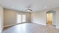 Located at 2121 Langhorne Rd in Lynchburg, Virginia, this single-story, 3-bedroom, 2-bathroom home delivers a clean, modern aesthetic with consistent finishes throughout. The open-concept kitchen and living area serves as the heart of the home, featuring grey shaker-style cabinetry, stainless steel appliances, a white subway tile backsplash, a center island with a built-in sink and white countertop, and stylish matte black pendant lighting. Light-toned luxury vinyl plank flooring flows through the main living areas, complemented by neutral warm-grey walls and white crown molding. The spacious living room includes a ceiling fan with light fixture and French doors that invite natural light and outdoor access. The generously sized primary bedroom continues the refined palette, while the additional bedrooms feature plush carpeting, ceiling fans, and large windows fitted with blinds for natural light and privacy. The bathrooms are finished with light LVP flooring, clean white fixtures, and a tub-shower combination. A dedicated laundry room houses a full-size washer and dryer. Multiple closets and hallways provide practical storage throughout. Recessed lighting adds a polished touch to the overall ambiance of this move-in-ready home.