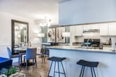 Located at 7980 Hampton Blvd in North Lauderdale, FL, this 2-bedroom, 2-bathroom residence offers a thoughtfully designed single-story layout that balances comfort and modern style. The open-concept living area features wood-look flooring, a neutral color palette accented with navy blue décor, and large sliding glass doors dressed with patterned curtains that invite abundant natural light and provide access to the outdoors. The living space flows seamlessly into a dedicated dining area illuminated by a chandelier, creating an ideal setting for entertaining. The galley-style kitchen is equipped with stainless steel appliances, white cabinetry, ample counter space, and tile flooring, offering a functional and efficient workspace. Both bedrooms are carpeted and feature ceiling fans, generous closet space, and large windows with vertical blinds. The primary bedroom is highlighted by a bold teal accent wall and direct access to its en-suite bathroom. Both bathrooms are finished with wood-look vinyl flooring, white vanity cabinetry with contemporary hardware, and shower-tub combinations, presenting a clean and cohesive aesthetic throughout. This residence combines practical design with inviting interiors, making it a well-appointed home in the North Lauderdale community.