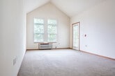 Located at 801 O'Keeffe Ave in Sun Prairie, Wisconsin, this 2-bedroom, 1-bathroom unit offers a practical and well-appointed single-floor layout. The open-concept kitchen and living area serves as the heart of the home, where warm oak cabinetry, a double-basin sink, a peninsula with extended countertop seating, and a dishwasher define the kitchen space. Tile flooring transitions into plush carpeting in the living room, which features striking vaulted ceilings, a ceiling fan, and a large window that fills the room with natural light. A pendant light adds a finishing touch to the kitchen area. Both bedrooms are carpeted and offer generous closet space, including a wide wall closet with wire shelving in the primary bedroom. The full bathroom features tile flooring, a long oak vanity with an integrated sink, a large mirror, and a baseboard heater. An in-unit laundry room includes overhead cabinetry and houses a full-size washer and dryer. A private balcony with a white railed railing overlooks a landscaped setting with mature trees, providing a peaceful outdoor retreat. The brick exterior and tree-lined surroundings contribute to the overall charm of this Sun Prairie residence.