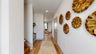 Located at 30 Tanner Rd in Greenville, SC, this well-appointed two-story home offers a thoughtful layout across two floors. The main level provides a welcoming living area with light hardwood flooring, crisp white walls, and a ceiling fan that adds an airy, open feel. The modern kitchen is a standout feature, showcasing white cabinetry with dark hardware, sleek quartz countertops, stainless steel appliances, and a light-filled window that brings in natural daylight. A dedicated office space on this level offers a quiet retreat for work or study. The upper floor hosts three bedrooms, including a primary suite with natural light streaming through large windows and a walk-in closet complete with wire shelving systems and plush carpet. Three full bathrooms are finished with dual-sink vanities, wood-toned flooring, and clean, contemporary fixtures. A dedicated laundry room with full-size washer and dryer adds everyday convenience. The attached garage provides secure parking and additional storage. Throughout the home, neutral tones, hardwood-style flooring, and panel-style doors create a cohesive and modern aesthetic that is both functional and inviting.