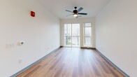 Located at 2200 Alpha Dr in Bridgeville, PA, this thoughtfully designed one-bedroom, one-bathroom unit offers a clean, modern aesthetic throughout. Warm wood-look plank flooring runs continuously across the entire floor plan, complemented by crisp white walls and gray-trimmed panel doors that add a contemporary touch.

The open-concept kitchen and living area forms the heart of the unit. The kitchen is well-appointed with white shaker cabinetry, a herringbone-patterned tile backsplash, quartz countertops, and a full suite of stainless steel appliances including a French door refrigerator, electric range, microwave, and dishwasher. A large central island with pendant globe lighting provides additional prep space and casual seating. The living area flows seamlessly from the kitchen and features a ceiling fan and sliding glass doors that open to a private balcony, filling the space with natural light and outdoor views.

The bedroom is a comfortable, well-proportioned room with a window offering natural light and built-in shelving for added storage. The bathroom is clean and functional, featuring a full tub-shower combination with dark hardware accents and wood-look flooring. A dedicated laundry room houses a full-size top-load washer and dryer, adding everyday convenience to this move-in-ready unit.