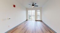 Located at 2200 Alpha Dr in Bridgeville, PA, this thoughtfully designed one-bedroom, one-bathroom unit offers a clean, modern aesthetic throughout. Warm wood-look plank flooring runs continuously across the entire floor plan, complemented by crisp white walls and gray-trimmed panel doors that add a contemporary touch.

The open-concept kitchen and living area forms the heart of the unit. The kitchen is well-appointed with white shaker cabinetry, a herringbone-patterned tile backsplash, quartz countertops, and a full suite of stainless steel appliances including a French door refrigerator, electric range, microwave, and dishwasher. A large central island with pendant globe lighting provides additional prep space and casual seating. The living area flows seamlessly from the kitchen and features a ceiling fan and sliding glass doors that open to a private balcony, filling the space with natural light and outdoor views.

The bedroom is a comfortable, well-proportioned room with a window offering natural light and built-in shelving for added storage. The bathroom is clean and functional, featuring a full tub-shower combination with dark hardware accents and wood-look flooring. A dedicated laundry room houses a full-size top-load washer and dryer, adding everyday convenience to this move-in-ready unit.
