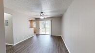 Located in West Lafayette, Indiana, this single-floor, one-bedroom, one-bathroom unit offers a well-organized layout across a compact but efficiently designed floor plan. The living room is bright and open, featuring dark hardwood-style flooring, neutral gray walls, a textured ceiling, and a ceiling fan with integrated lighting. A sliding glass door floods the space with natural light and provides direct access to outdoor views, enhancing the sense of openness. The galley-style kitchen is equipped with dark espresso cabinetry, granite-look countertops, black appliances including a refrigerator, range, and microwave, and a stainless steel sink. A louvered bifold closet door in the kitchen area provides convenient additional storage. The bedroom offers comfortable wall-to-wall carpeting, a ceiling fan, a louvered bifold closet, and a window that brings in natural light. A walk-in closet is also accessible from the bedroom, providing ample storage. The bathroom features a tiled shower-tub combination and a vanity with light countertops. Hardwood-style flooring extends through the main living areas, while plush carpet adds warmth to the bedroom, creating a cohesive and practical interior throughout.