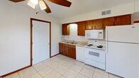 Located at 3306 Jamesdale Rd in Columbia, Missouri, this single-floor unit offers a practical and well-organized layout accommodating three bedrooms, one full bathroom, a kitchen, a laundry area, and a connecting hallway. The kitchen is equipped with warm wood cabinetry, a double-basin sink, tile backsplash, and white appliances including an electric range, built-in microwave, and refrigerator. Light tile flooring and a ceiling fan complete the space. The bedrooms feature neutral carpet flooring and warm wood trim throughout, providing a consistent and cohesive aesthetic. The primary bedroom includes a double sliding-door closet, offering ample storage. A secondary bedroom opens to an outdoor patio via French doors, bringing in natural light and outdoor access. The third bedroom features a window with views of surrounding greenery. The full bathroom includes a tiled tub-shower combination with clean white finishes. The laundry area houses a water heater and washer hookups on tile flooring. Textured ceilings are found throughout the unit, and warm wood door and baseboard trim ties the interior together. An outdoor patio and lawn area are accessible directly from the unit.