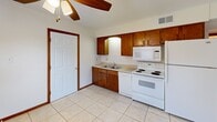 Located at 3306 Jamesdale Rd in Columbia, Missouri, this single-floor unit offers a practical and well-organized layout accommodating three bedrooms, one full bathroom, a kitchen, a laundry area, and a connecting hallway. The kitchen is equipped with warm wood cabinetry, a double-basin sink, tile backsplash, and white appliances including an electric range, built-in microwave, and refrigerator. Light tile flooring and a ceiling fan complete the space. The bedrooms feature neutral carpet flooring and warm wood trim throughout, providing a consistent and cohesive aesthetic. The primary bedroom includes a double sliding-door closet, offering ample storage. A secondary bedroom opens to an outdoor patio via French doors, bringing in natural light and outdoor access. The third bedroom features a window with views of surrounding greenery. The full bathroom includes a tiled tub-shower combination with clean white finishes. The laundry area houses a water heater and washer hookups on tile flooring. Textured ceilings are found throughout the unit, and warm wood door and baseboard trim ties the interior together. An outdoor patio and lawn area are accessible directly from the unit.