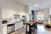 Located at 726 Fulton St in Chattanooga, TN, this one-bedroom, one-bathroom unit offers a well-designed open-concept layout across a single floor. The combined kitchen and living area forms the heart of the unit, showcasing impressively tall ceilings that lend an airy, expansive feel. The kitchen is outfitted with crisp white shaker cabinetry, granite countertops, a classic subway tile backsplash, and a full suite of stainless steel appliances, including a dishwasher, range, and microwave. Wood-look flooring runs throughout the main living space, complementing the bright, neutral color palette. The living area benefits from natural light through a large window with urban views, and is anchored by a ceiling fan overhead. The bedroom is a comfortable, carpeted retreat with its own window overlooking the surrounding cityscape and direct access to the bathroom. The bathroom features granite countertops, white cabinetry, a tiled tub/shower combination, and stylish tilework on the floor. Two closets provide ample storage, and a dedicated utility room adds practical convenience. The overall aesthetic is modern and clean, with contemporary finishes throughout.
