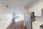 Located on the third floor at 1465 Commonwealth Ave in Boston's Brighton neighborhood, this one-bedroom, one-bathroom unit offers a well-designed layout with modern finishes throughout. Rich, dark hardwood flooring flows consistently across the living areas, hallway, and bedroom, creating a cohesive and polished aesthetic.

The kitchen is a standout feature, outfitted with white shaker-style cabinetry extending to the ceiling for ample storage, light stone countertops, a subway tile backsplash, and a full suite of stainless steel appliances including a refrigerator, gas range, microwave, and dishwasher. Recessed lighting illuminates the space effectively.

The open living area extends from the kitchen and is bathed in natural light from large windows, with track lighting adding additional flexibility. The bedroom is a comfortable, well-proportioned room featuring its own window with a shade, dark hardwood floors, and easy access to the unit's three closets, providing generous storage throughout.

The bathroom is clean and contemporary, featuring light wood-look tile flooring, a floating vanity with gray cabinetry, white countertop, a large mirror, and grab bars — combining accessibility with style. A welcoming hallway connects all rooms, completing this efficiently planned and thoughtfully finished urban residence.