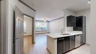 Located at 1200 Reserve Dr NE in Brookhaven, GA, this one-bedroom, one-bathroom residence offers a thoughtfully designed single-floor layout. Light wood-tone flooring flows throughout, creating a cohesive and inviting atmosphere. The open-concept living and kitchen area forms the heart of the home, where a peninsula with a white countertop and undermount sink separates the two spaces. The kitchen is equipped with dark cabinetry, stainless steel appliances including a refrigerator and range, and recessed lighting overhead. The living room benefits from a ceiling fan and a large window that draws in generous natural light, with views of surrounding greenery. The spacious bedroom also features a ceiling fan, a large window with outdoor views, and ample room for furnishings. A dedicated closet provides convenient storage. The full bathroom includes a tub-shower combo with tile surround, dark vanity cabinetry with a white countertop, and a window for natural ventilation. An in-unit laundry area houses a full-size top-loading washer and dryer with overhead shelving for added functionality. Crown molding details add a refined touch throughout this well-appointed Brookhaven residence.