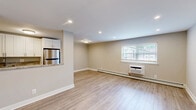 Located at 1300 Fayette St in Conshohocken, PA, this one-bedroom, one-bathroom unit offers a well-organized single-floor layout with a practical and modern interior design throughout. The open living and kitchen area is finished with light wood-tone luxury vinyl flooring and neutral gray walls, creating a bright and clean atmosphere. Recessed lighting illuminates the space effectively, complementing the natural light that filters through the windows. The kitchen is a standout feature, appointed with crisp white shaker-style cabinetry extending to the ceiling for ample storage, granite countertops with striking natural veining, and a full suite of stainless steel appliances including a gas range, over-the-range microwave, dishwasher, and refrigerator. The bedroom is a comfortable size, carpeted for warmth, and includes a ceiling fan, a wall-mounted air conditioning unit, and a window with views of the surrounding greenery. An additional room with hardwood-style flooring, recessed lighting, and a window offers flexible use as a den or office. The bathroom is finished with large-format neutral tile surrounding a deep soaking tub with a rain showerhead and sleek chrome fixtures. A hallway connects the rooms, completing this efficiently designed and thoughtfully updated residence.