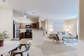 Located at 119 Lakeview Dr in Crestview, Florida, this single-story residence offers a thoughtfully designed open-concept floor plan that connects the kitchen, dining, and living areas into one cohesive space. The kitchen is outfitted with rich dark-wood cabinetry, granite-style countertops, a stainless steel refrigerator, black appliances including a range and built-in microwave, and stone-tile flooring. A peninsula with a breakfast bar provides additional prep space and acts as a natural divider between the kitchen and the adjacent dining area. The living room features plush wall-to-wall carpeting, neutral warm-toned walls, and large windows with elegant curtains that allow ample natural light. A private exterior door off the living area provides convenient outdoor access. Both bedrooms are carpeted and generously sized, each benefiting from large windows that enhance the sense of space and brightness. The bathroom includes a combination tub and shower, a dark wood vanity with an undermount sink, stone-tile flooring, and built-in open shelving for storage. Throughout, the space maintains a cohesive, neutral palette that creates a calm and welcoming ambiance.