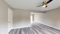 Located at 1005 McCord Rd in Valparaiso, Indiana, this thoughtfully updated home presents a clean, modern aesthetic throughout. The interior features luxury vinyl plank flooring in neutral grey and wood tones, flowing consistently across all rooms and complemented by crisp white trim and soft, warm-grey wall tones.

The kitchen stands out as a highlight of the home, boasting white shaker-style cabinetry, bright white countertops, a tile backsplash, recessed lighting, and a full suite of stainless steel appliances including a refrigerator, range, microwave, and dishwasher. A window above the sink brings in natural light and views of the outdoors.

The open living area is generously proportioned, featuring a ceiling fan with light fixture and an open flow into adjacent spaces, creating a welcoming and functional layout. Multiple bedrooms are well-sized, each equipped with ceiling fans and windows that allow natural light and outdoor views to filter in. Closet storage is present, with at least one room offering a spacious reach-in closet with a full-width hanging rod.

The bathroom is clean and functional, featuring a tub/shower combo with shelving, brushed nickel fixtures, a white vanity, and matching LVP flooring. A staircase with wood-toned treads and white risers provides additional access within the home.