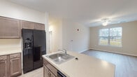 Located at 1610 N Hilton St in Baltimore, MD, this single-floor residence offers a thoughtfully designed layout with modern finishes and a neutral color palette throughout. The open-concept kitchen is a standout feature, equipped with rich dark-toned cabinetry, light quartz-style countertops, black appliances including a French door refrigerator with ice dispenser, an electric range with over-the-range microwave, and a dishwasher. A peninsula with a stainless steel sink and breakfast bar seating connects the kitchen seamlessly to the living area, which features light hardwood-style flooring, a ceiling fan, and a large window that fills the space with natural light. The bedrooms are carpeted and well-lit, each with ceiling fans and windows offering outdoor views of the surrounding neighborhood. The bathroom is finished with tile flooring, a dark wood vanity with a white countertop, and a large mirror with vanity lighting. A dedicated laundry room with tile flooring and washer/dryer hookups adds everyday convenience. Throughout the residence, clean white trim, neutral walls, and consistent hardwood-style and tile flooring create a cohesive, move-in-ready aesthetic.