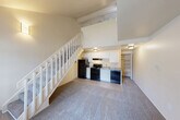 Located at 2486 Green Pine Dr in Burton, Michigan, this two-story residence offers a well-organized layout across two levels. The main floor serves as the primary living area, featuring a carpeted living room with a front entry door and a large window that brings in natural light. A white-railed staircase is a central architectural feature, leading to the upper level. The kitchen, which flows into the dining area, is equipped with black appliances including a refrigerator, stove, and dishwasher, complemented by white cabinetry, a granite-style countertop, and a sink. An open shelving pantry area is conveniently accessible adjacent to the kitchen. Baseboard heating units are present throughout the main floor, ensuring year-round comfort. Upstairs, the spacious bedroom features plush carpet, a ceiling fan with light fixture, and a closet with bi-fold doors offering ample storage. The upper level also includes a window providing natural light and an open loft-style overlook. The full bathroom is finished with tile flooring, a tub/shower combo with a white surround, and clean white fixtures. This residence offers a practical and comfortable layout suited for everyday living.