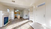This single-floor residence offers a thoughtfully designed open-concept layout that seamlessly connects the main living areas. The entryway welcomes you with tile flooring and a transom-windowed front door that draws in natural light, alongside a built-in shelving unit ideal for storage and display.

The living room is a standout space, featuring hardwood-style flooring, multiple large windows with views of the surrounding neighborhood, and a tile-surround fireplace that serves as a natural focal point. The room receives generous sunlight throughout the day, creating a bright and inviting atmosphere.

The kitchen is well-appointed with light wood cabinetry, white countertops, and a full suite of white appliances including a range, dishwasher, and refrigerator. A central island provides additional prep and dining space, while a window above the sink adds natural light. The kitchen flows naturally into the main living area, reinforcing the open-plan design.

The bedrooms feature plush carpeting and ample windows, offering comfortable, light-filled retreats. Additional functional elements include visible HVAC venting and an accessible electrical panel. Throughout the residence, neutral wall tones and consistent finishes contribute to a cohesive, clean aesthetic.