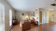 This two-story, 2-bedroom, 2-bathroom home offers a functional and comfortable layout spread across two floors. The main level features warm hardwood flooring throughout the living room, dining room, and kitchen. The living room is finished with crown molding and a textured ceiling, creating a polished atmosphere, while a decorative sunburst mirror and ample lighting add character to the space. The adjacent dining area benefits from natural light through a large window and provides an intimate setting for meals. The kitchen is equipped with white cabinetry, granite-style countertops, and a full-size black refrigerator. A full bathroom with a tub-shower combo is also located on the main level. Upstairs, both bedrooms are carpeted and filled with natural light from multiple windows. The spacious primary bedroom includes a ceiling fan and generous proportions, while the second bedroom features a closet with sliding doors. Each floor includes a full bathroom with tub-shower combinations. A dedicated in-unit laundry room with built-in wire shelving provides added convenience. Two closets offer practical storage throughout the home. The neutral color palette and consistent finishes create a cohesive, move-in-ready environment throughout.