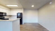 This single-floor unit offers a clean, functional layout designed for comfortable everyday living. The open-concept living area greets you at the entrance, featuring durable wood-style plank flooring, neutral-toned walls, and a textured ceiling with a ceiling fan — creating a bright and airy atmosphere. The kitchen is well-equipped with crisp white cabinetry, light speckled countertops, and a full suite of black appliances including a refrigerator, range, over-the-range microwave, and dishwasher. A peninsula counter separates the kitchen from the living space, offering a casual dining or prep area. The unit includes multiple bedrooms, each finished with the same wood-style flooring, textured ceilings, and neutral walls. One bedroom benefits from a window that brings in natural light and outdoor views. The bathroom features a wide vanity with white cabinetry, a speckled countertop, a large wall mirror, and a medicine cabinet, providing ample storage and a clean, practical design. Consistent finishes throughout — including white trim, neutral paint tones, and wood-style flooring — give the unit a cohesive and move-in ready feel.