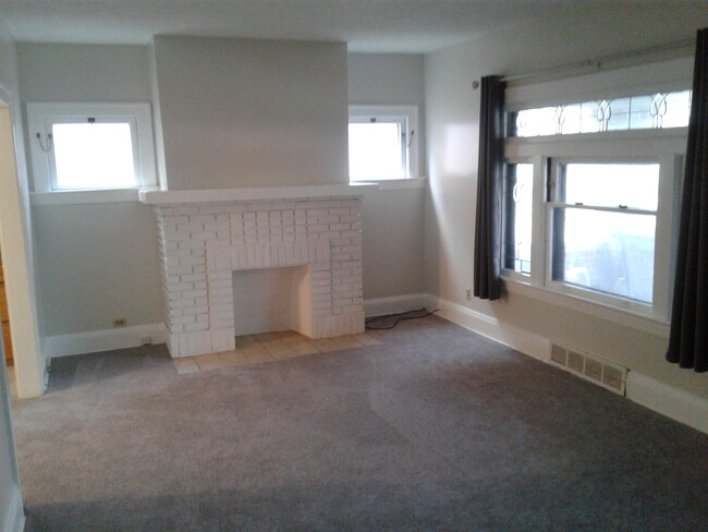 The large living room with newer carpet and paint. Nice decorative fireplace and a walk-in closet. - 1673 Victoria Ave