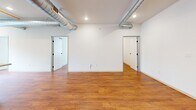 Located at 305 N 3rd St in Burlington, Iowa, this two-bedroom, one-bathroom unit offers a thoughtfully designed open-concept layout with warm hardwood flooring throughout. The space blends industrial character with modern finishes, highlighted by exposed metal ductwork running across the ceiling alongside recessed lighting and stylish pendant fixtures.

The kitchen serves as a central hub of the unit, featuring white shaker cabinetry, a marble-topped center island, stainless steel appliances including a range, microwave, dishwasher, and refrigerator, all complemented by pendant lighting overhead. The open flow connects seamlessly to the main living area, creating a versatile and functional space.

Both bedrooms are bright and airy, each with large windows dressed with roller shades that allow natural light to fill the rooms while offering views of Burlington's historic downtown streetscape. The bedroom closets feature sliding panel doors, providing clean, minimalist storage.

The bathroom is finished in white with hardwood flooring, a modern vanity with under-cabinet storage, and a round mirror. An in-unit washer and dryer are conveniently accessible nearby. The overall ambiance is clean, contemporary, and functional, with an urban loft aesthetic rooted in the character of a historic downtown building.