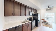 Located at 1310 E St Louis St in Springfield, MO, this one-bedroom, one-bathroom unit offers a well-designed, efficient layout across a single floor. Light wood-tone flooring runs throughout, creating a clean and cohesive aesthetic that ties each room together seamlessly.

The galley-style kitchen is a standout feature, showcasing rich dark-brown cabinetry extending floor to ceiling, a classic white subway tile backsplash, light countertops, and a full suite of black appliances including a refrigerator, electric range with overhead microwave, and dishwasher. The kitchen opens directly into the combined living and dining area, promoting an open, connected feel.

The living room is bright and airy, benefiting from a large sliding glass door that leads to a private balcony, allowing generous natural light to fill the space. A ceiling fan and wall-mounted HVAC unit provide year-round comfort.

The bedroom is a calm, well-proportioned retreat featuring a window with blinds, recessed lighting, and its own wall-mounted HVAC unit. A dedicated closet provides practical storage.

The bathroom is clean and straightforward, offering a full tub-shower combination, light wood-tone flooring, and crisp white finishes. The overall design of the unit prioritizes functionality and modern simplicity throughout.