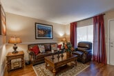 Located at 12801 Champion Forest Dr in Houston, TX, this 1-bedroom, 1-bathroom model unit is a single-story residence designed with comfort and style in mind. The living room sets a sophisticated tone with dark hardwood flooring, a rich leather sofa and armchair, a decorative area rug, and large windows dressed in deep burgundy drapes that invite natural light while maintaining a cozy atmosphere. A large framed landscape artwork anchors the main wall, adding a refined artistic touch.

The dining area features a round wooden table with matching chairs beneath a modern pendant light, complemented by a decorative wall mirror and chair rail molding that adds architectural character. An open pass-through connects the dining space to the kitchen, enhancing the flow of the layout.

The bedroom is a restful retreat, outfitted with plush carpeting, a ceiling fan with light fixture, and windows with blinds that allow for natural light. A substantial dark wood dresser with an ornate mirror and matching nightstands complete the classic furnishing ensemble.

The bathroom offers a clean, functional design with white cabinetry, a dark granite countertop, an undermount sink, a well-lit vanity mirror, and a combination shower/tub. The overall ambiance of this unit is warm and inviting, with consistent dark wood tones and neutral wall colors creating a cohesive, elegant feel throughout.