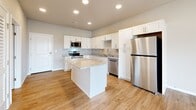 Located at 1735 E Valley Water Mill Rd in Springfield, MO, this one-bedroom, one-bathroom unit offers a thoughtfully designed single-floor layout. The open-concept kitchen and living area serves as the heart of the space, featuring crisp white shaker cabinetry, granite countertops, a central island, and a full suite of stainless steel appliances including a refrigerator, dishwasher, electric range, and over-the-range microwave. Recessed lighting illuminates the kitchen, while a ceiling fan anchors the living area. Light wood-style flooring flows throughout the main living spaces, complementing the neutral wall tones. Sliding glass doors lead to a private balcony, allowing natural light to pour into the living room. A hallway connects the main area to the bedroom, which features plush carpeting, a dedicated closet, and a window offering views of the surrounding community. The bathroom is conveniently accessible, and the unit also includes a laundry area and utility room for added practicality. Clean finishes, modern fixtures, and a well-organized floor plan make this unit a functional and comfortable living space.